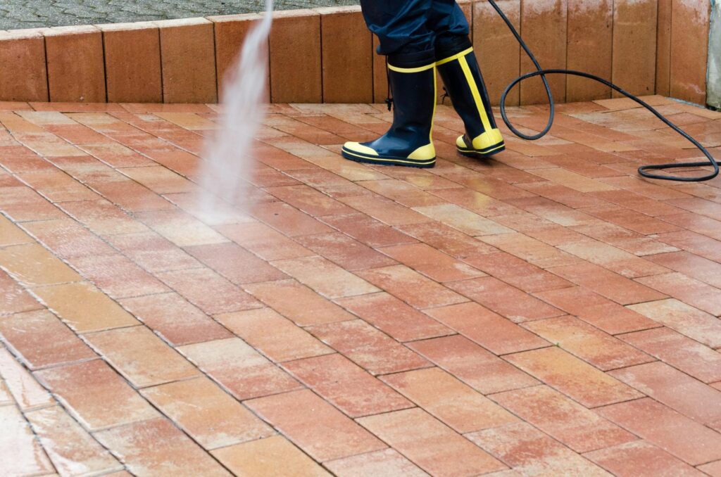 man power washing the concrete brick floor